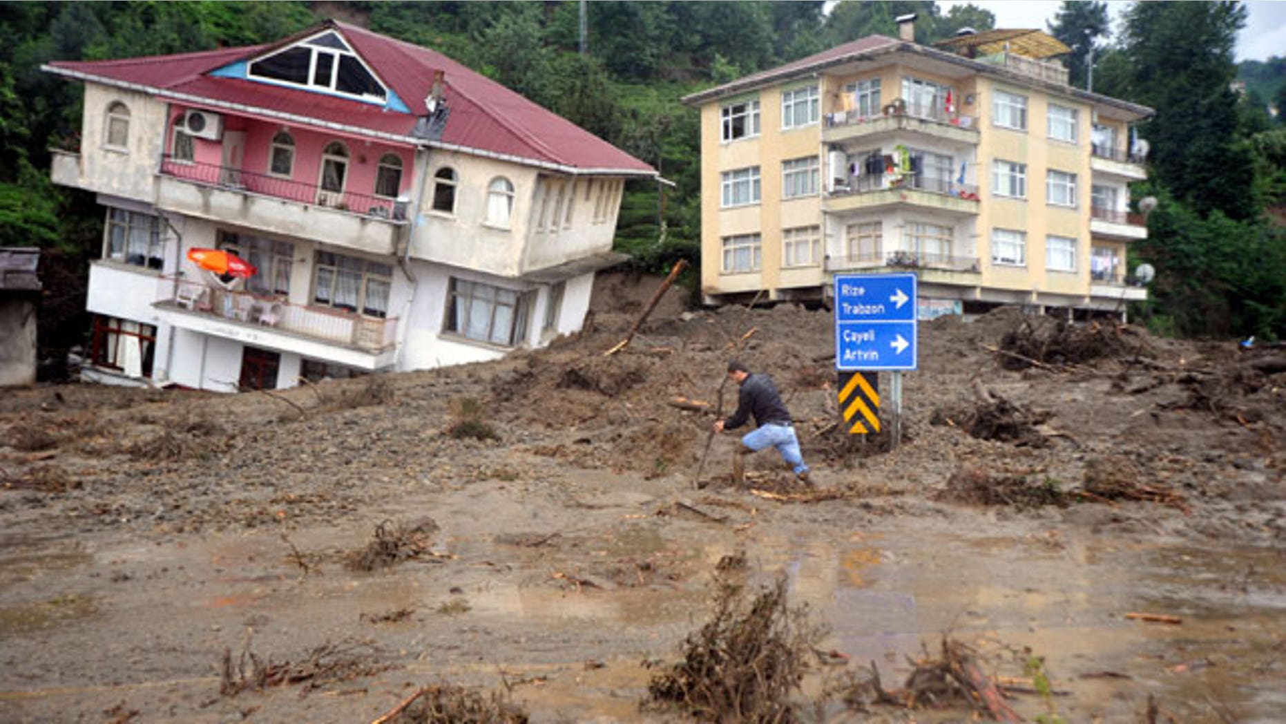 A man walks past a house tilted sideways after landslides and floods triggered by heavy rains swept through a Gundogdu near Turkey's Black Sea coast on Friday, Aug. 27, 2010. People were killed when the landslide collapsed homes in Gundogdu, in the tea-growing Black Sea province of Rize.