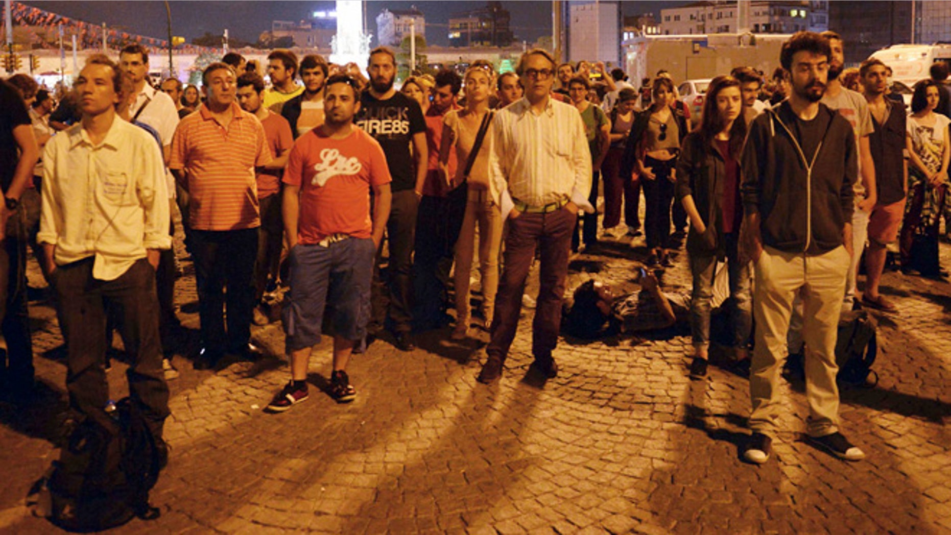 June 18, 2013: Erdem Gunduz, left, and dozens of people stand silently on Taksim Square in Istanbul, Turkey. After weeks of confrontation with police, sometimes violent, Turkish protesters are using a new form of resistance: standing silently. The development started late Monday when a solitary man began standing in passive defiance against Prime Minister Recep Tayyip Erdogan's authority at Istanbul's central Taksim Square.