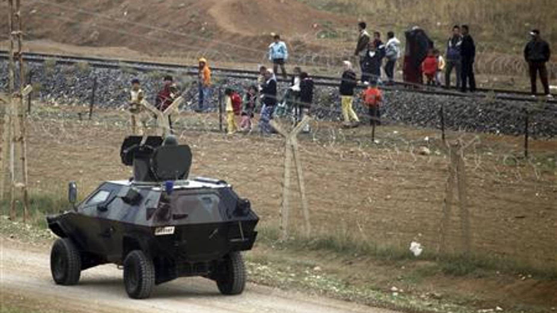 A Turkish soldier speaks with Syrian refugees who are trying to cross the border fence from the northern Syrian town of Ras al-Ain into Turkey.