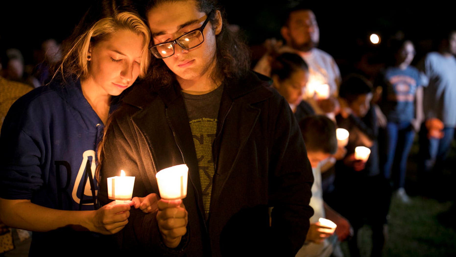 Bailey LeJeaune, 17, and David Betancourt, 18, hold candles during a vigil in Sutherland Springs for the victims of a deadly shooting at the First Baptist Church in Sutherland Springs, Texas, Sunday, Nov. 5, 2017. A man opened fire inside of the church in the small South Texas community on Sunday, killing more than 20 people. (Jay Janner/Austin American-Statesman via AP)
