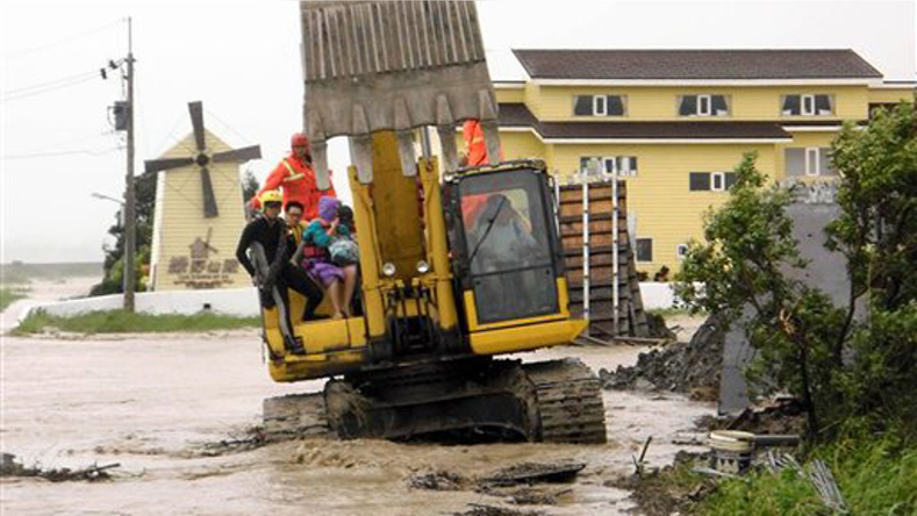 In this photo released by Hengchun Township Fire Department, residents are evacuated on an excavator as Typhoon Nanmadol began blowing toward Taiwan in Hengchu township, Pingtung county, southern Taiwan, Sunday, Aug. 28, 2011.