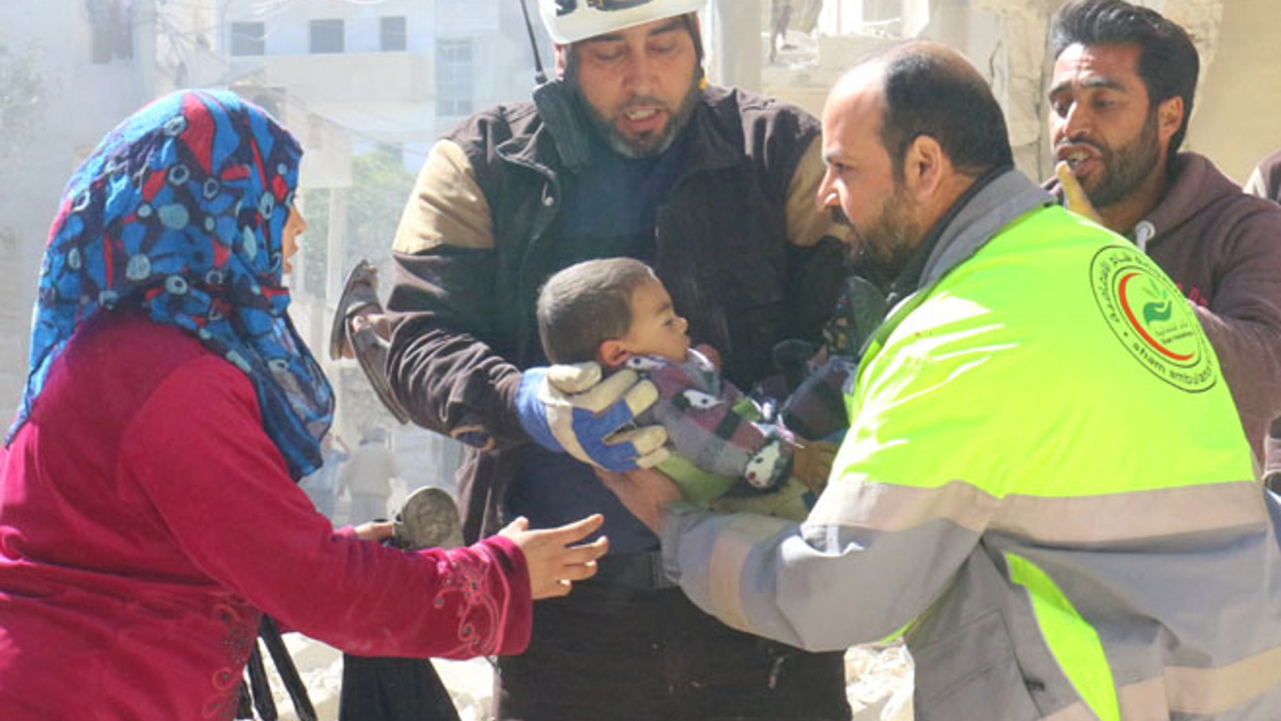 MARCH 19: People and a civil defence personnel carry a child who survived after an airstrike on rebel-held Idlib city.