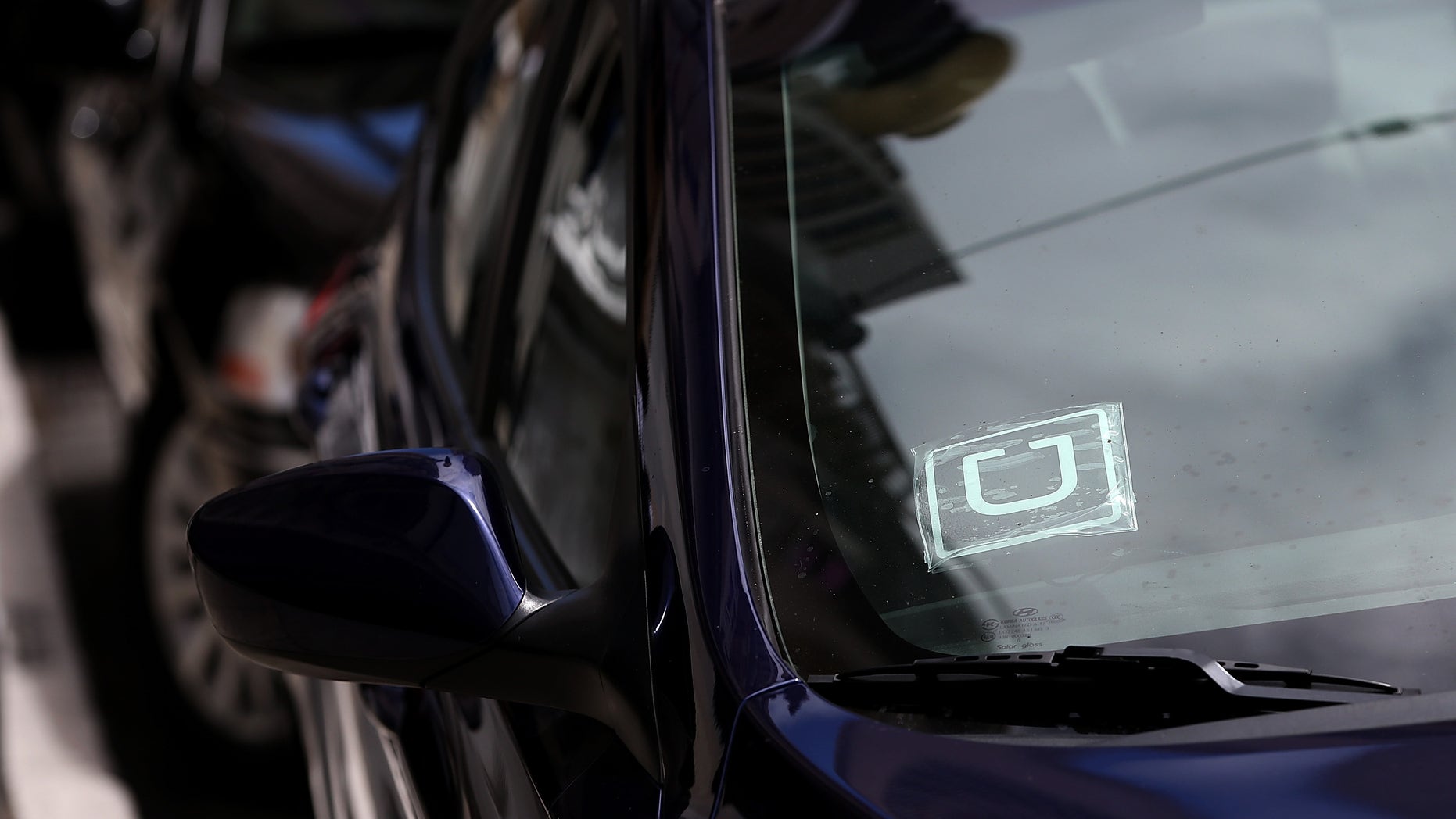 SAN FRANCISCO, CA - JUNE 12: A sticker with the Uber logo is displayed in the window of a car on June 12, 2014 in San Francisco, California. The California Public Utilities Commission is cracking down on ride sharing companies like Lyft, Uber and Sidecar by issuing a warning that they could lose their ability to operate within the state if they are caught dropping off or picking up passengers at airports in California. (Photo by Justin Sullivan/Getty Images)