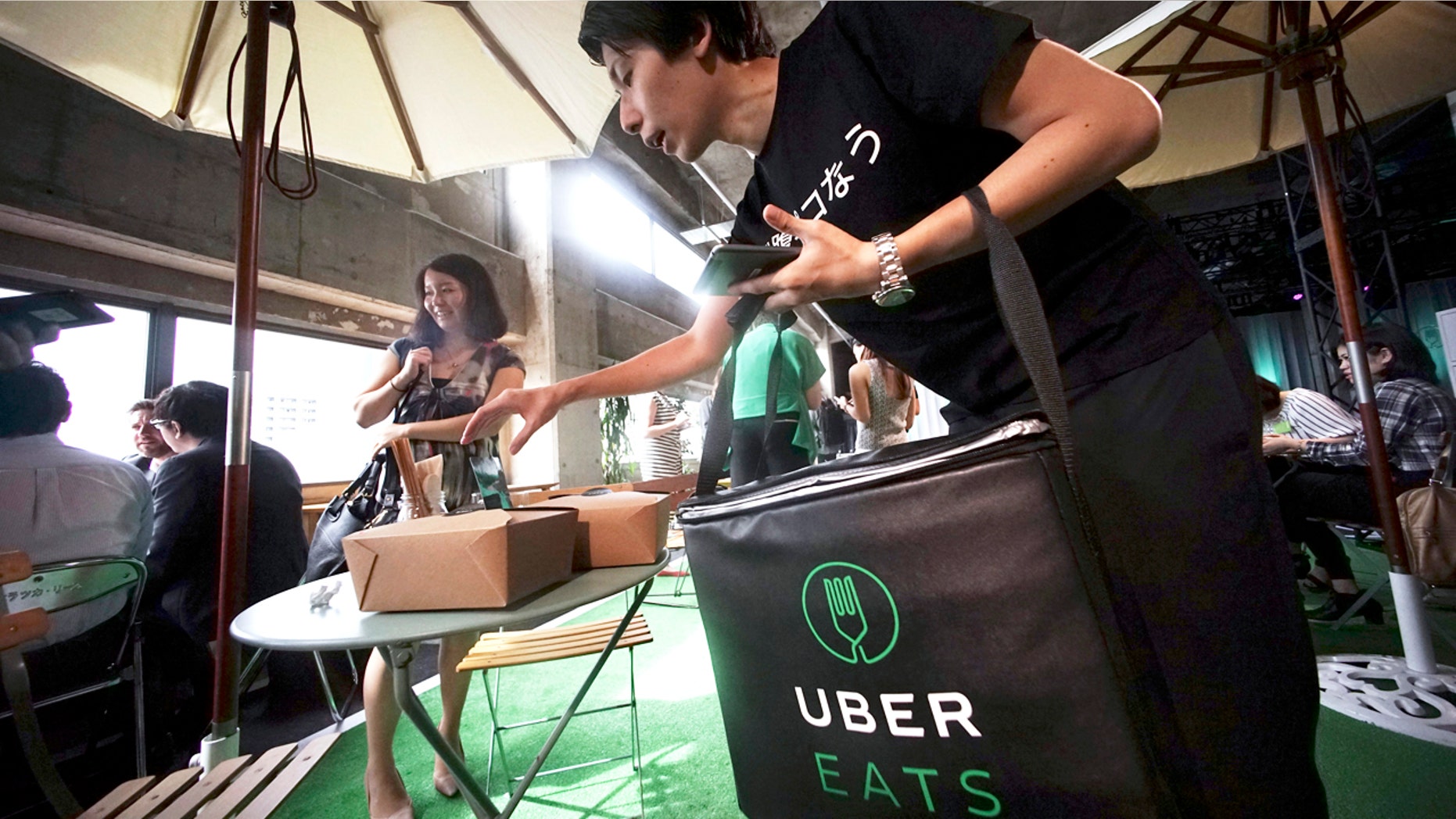 A delivery man brings ordered food during a press conference of UberEats in Tokyo, Wednesday, Sept. 28, 2016. Uber, which has struggled to win Japan over to its ride-sharing service, is hoping to fare better with takeout deliveries.