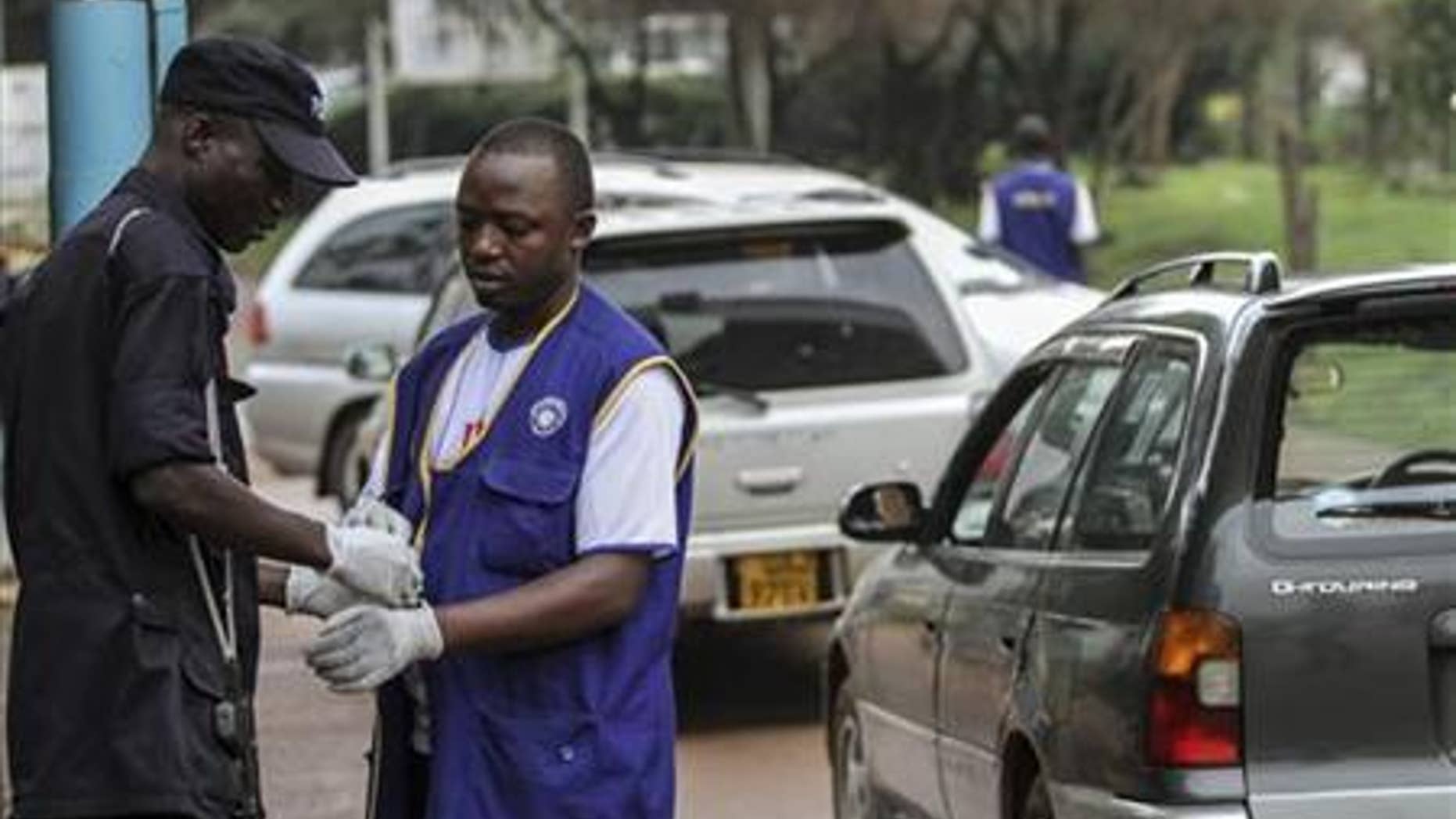 Security personnel wear gloves to check motorists entering and exiting Mulago hospital in Uganda's capital of Kampala July 31, 2012. REUTERS/Edward Echwalu