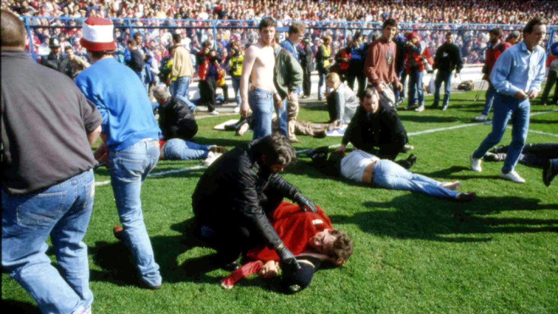 FILE - In this April 15, 1989 file photo, showing police, stewards and supporters as they tend to wounded soccer supporters on the field at Hillsborough Stadium, in Sheffield, England. 96 Liverpool fans were crushed to death in the incident at the FA Cup semi-final match Liverpool against Nottingham Forest.