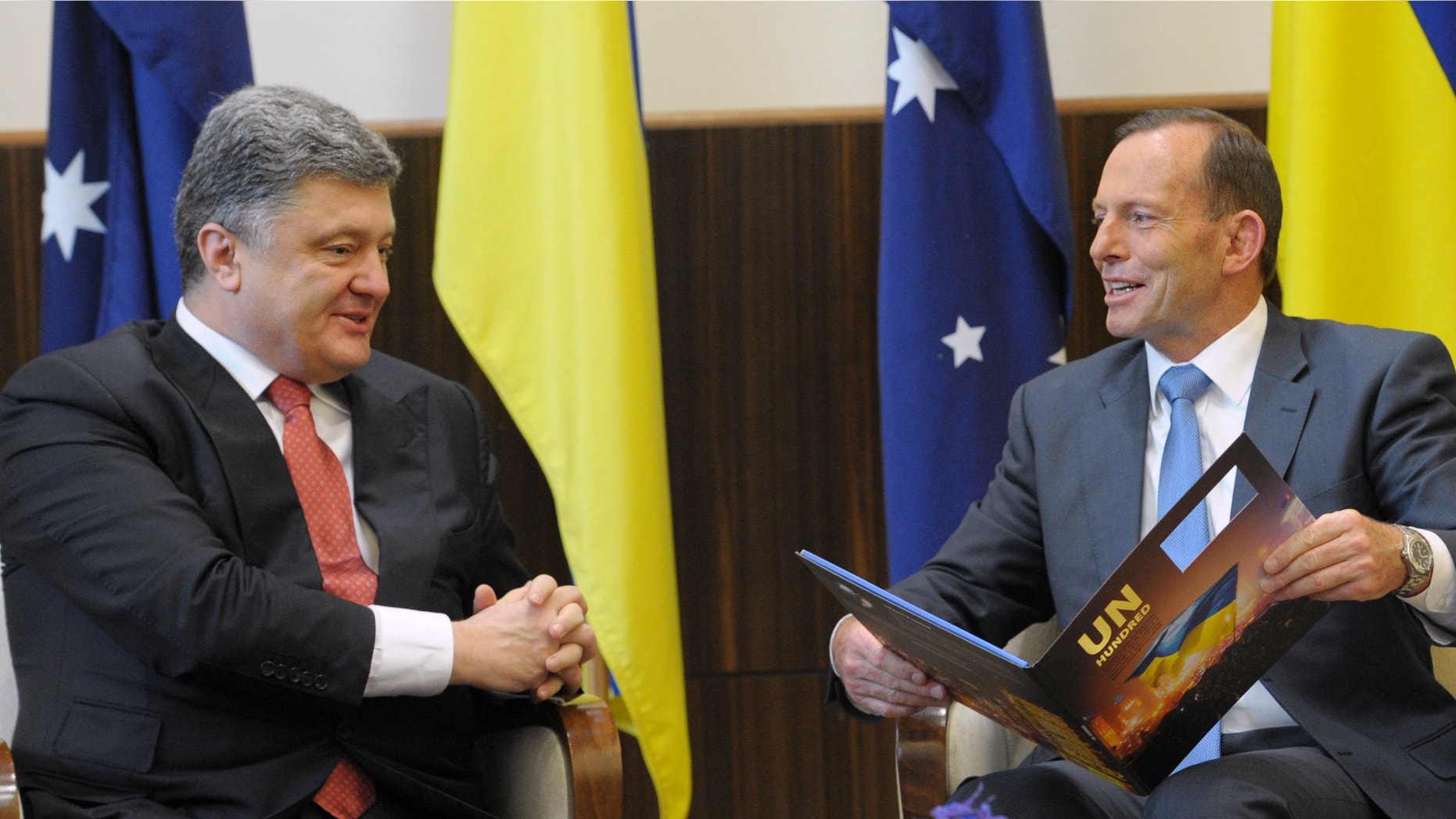 Dec. 11, 2014: Australian Prime Minister Tony Abbott, right, holds a book given to him by Ukrainian President Petro Poroshenko as they meet at the federal government office