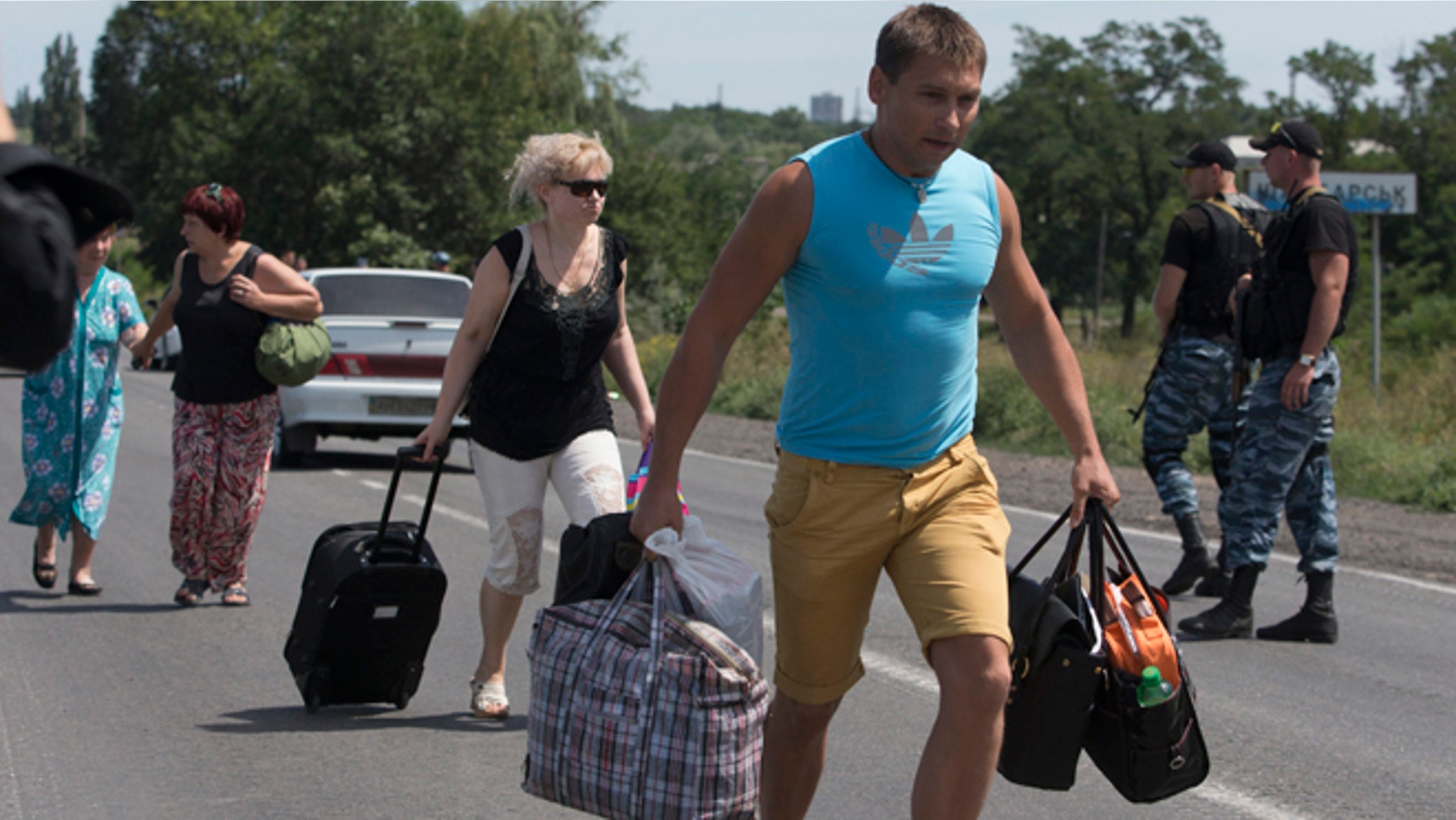 July 28, 2014: Self-proclamed Donetsk People's Republic policemen watch refugees fleeing Shakhtarsk, Donetsk region, eastern Ukraine. An international police team abandoned its attempt to reach the crash site of a Malaysia Airlines plane for a second day running Monday as clashes raged in a town on the road to the area.