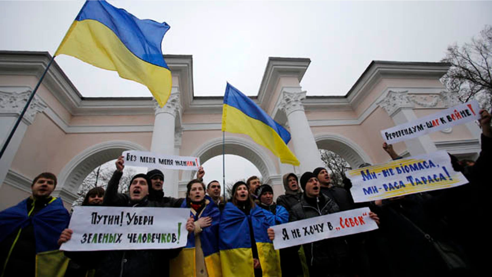 March 11, 2014: People hold Ukrainian flags and banners that read: "Putin! Take away the green men", "They got me married without me being there", "Referendum is a step to war", during a rally against the breakup of the country in Simferopol, Crimea, Ukraine.