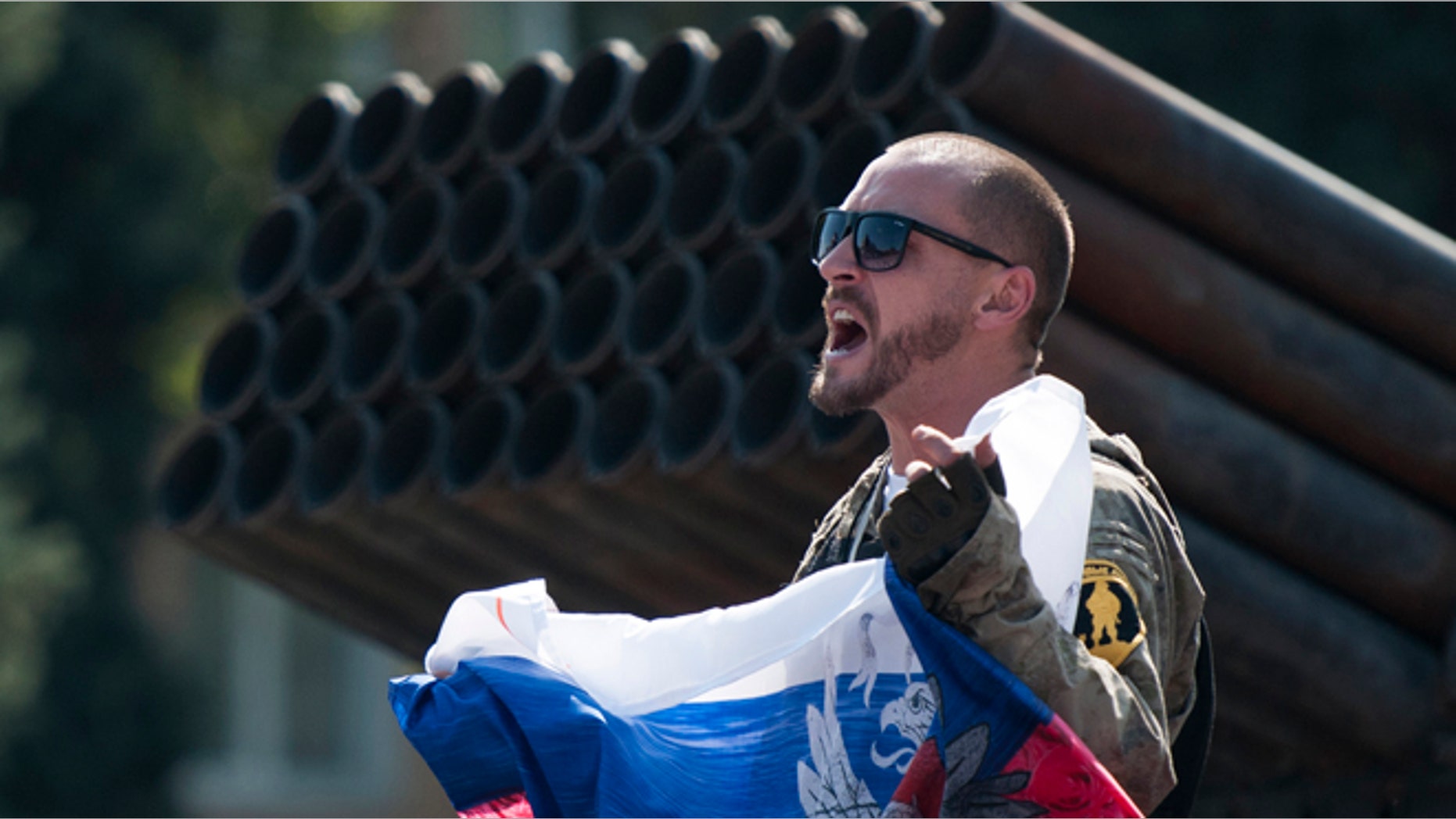 Aug. 24, 2014: A pro-Russian rebel holds a Russian national flag near to damaged heavy hardware from the Ukrainian army during an exhibition in the central square in Donetsk, eastern Ukraine. (AP/Antoine E.R. Delaunay)