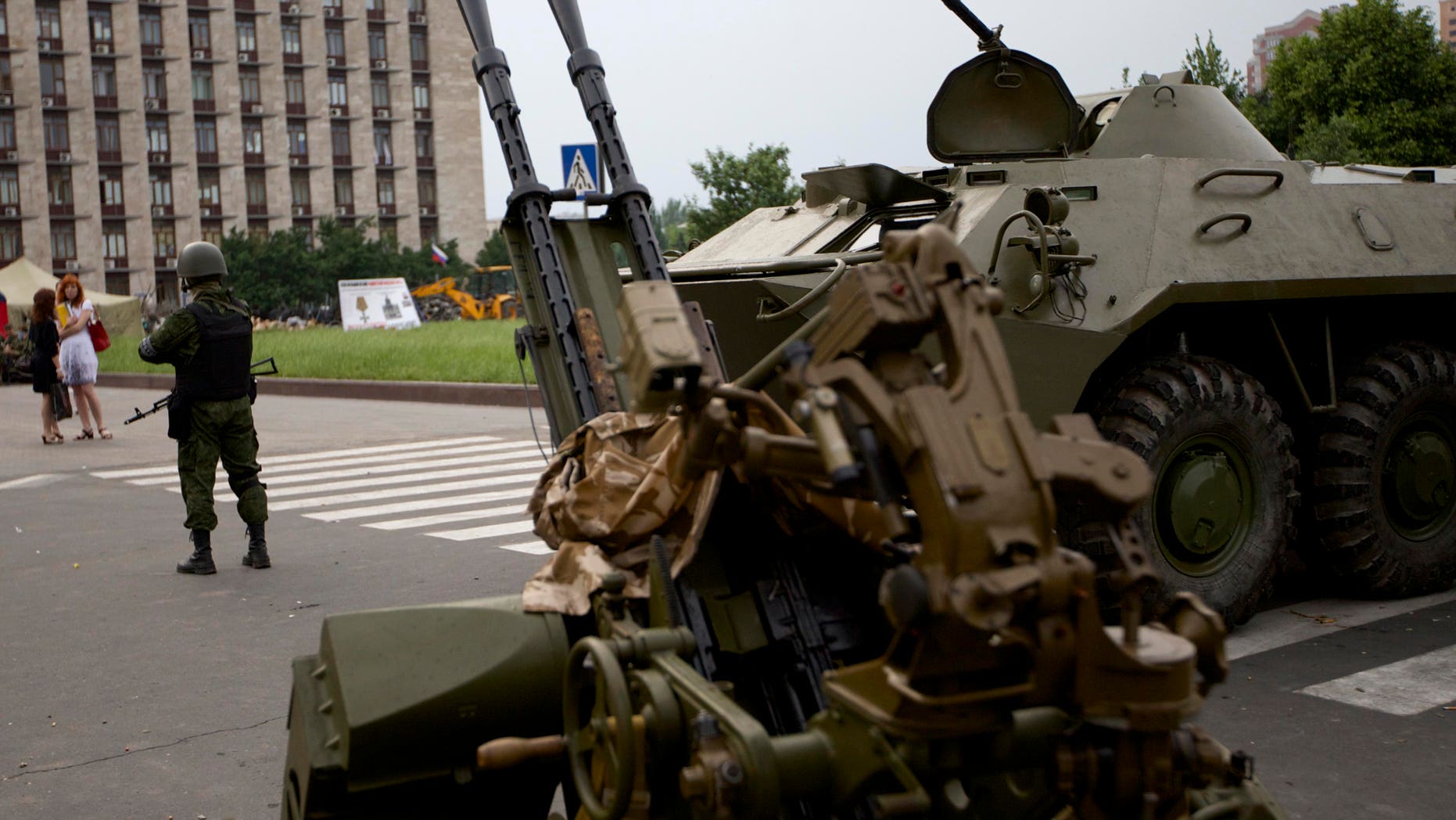 May 29, 2014: A Pro-Russian militia member guards next to an APC and anti-aircraft gun, outside the administrational building in Donetsk, Ukraine.
