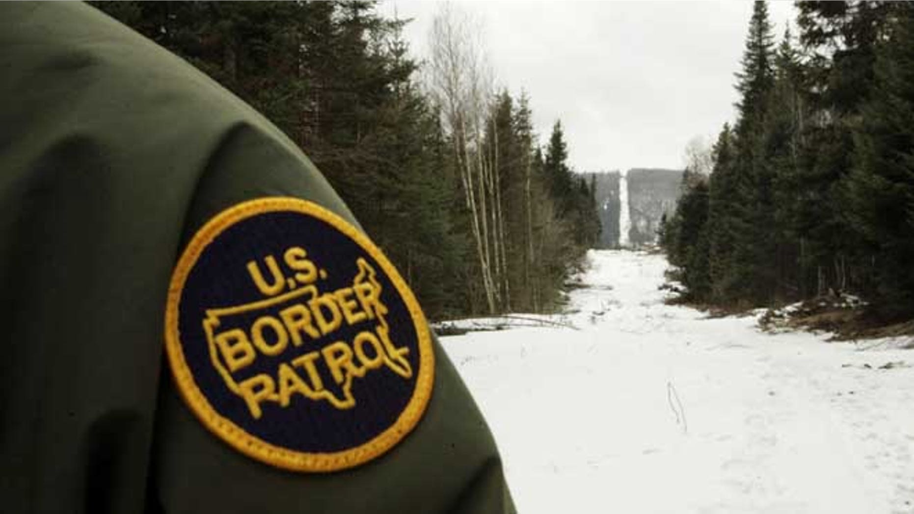 BEECHER FALLS, VT - MARCH 23: A U.S. Border Patrol agent stands along the boundary marker cut into the forest marking the line between Canadian territory on the right and the United States March 23, 2006 near Beecher Falls, Vermont. As American politicians continue to debate immigration reform, Border Patrol agents work the northern border to prevent illegal entry. (Photo by Joe Raedle/Getty Images)
