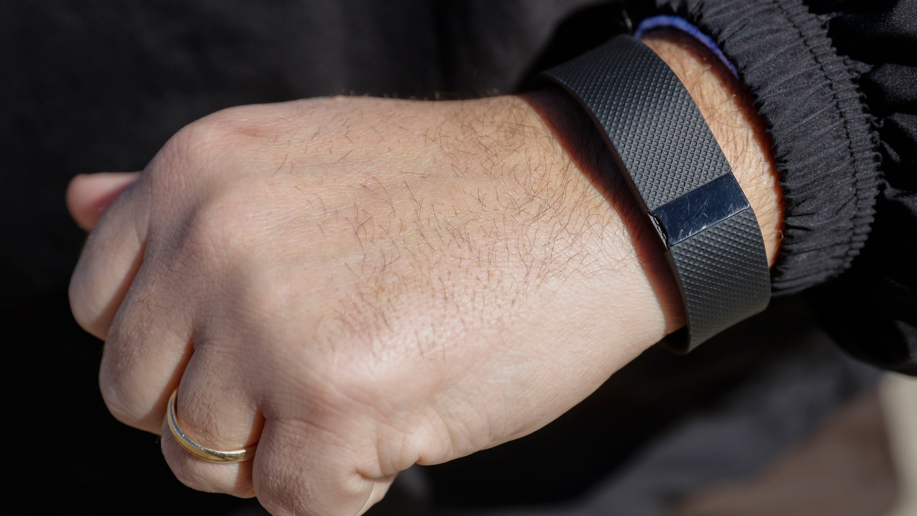 FILE - In this Monday, Feb. 29, 2016, file photo, Brett Broviak, a manager of respiratory and sleep services at IU Health North Hospital, shows off his Fitbit fitness tracker for the camera on the hospital's campus in Carmel, Ind. Wearing a stylish fitness tracker may help you keep tabs on things like how many steps you take, but the devices themselves _ even with the lure of a cash reward _ probably wonât improve your health, according to the biggest study yet done on the trendy technology. (AP Photo/AJ Mast, File)