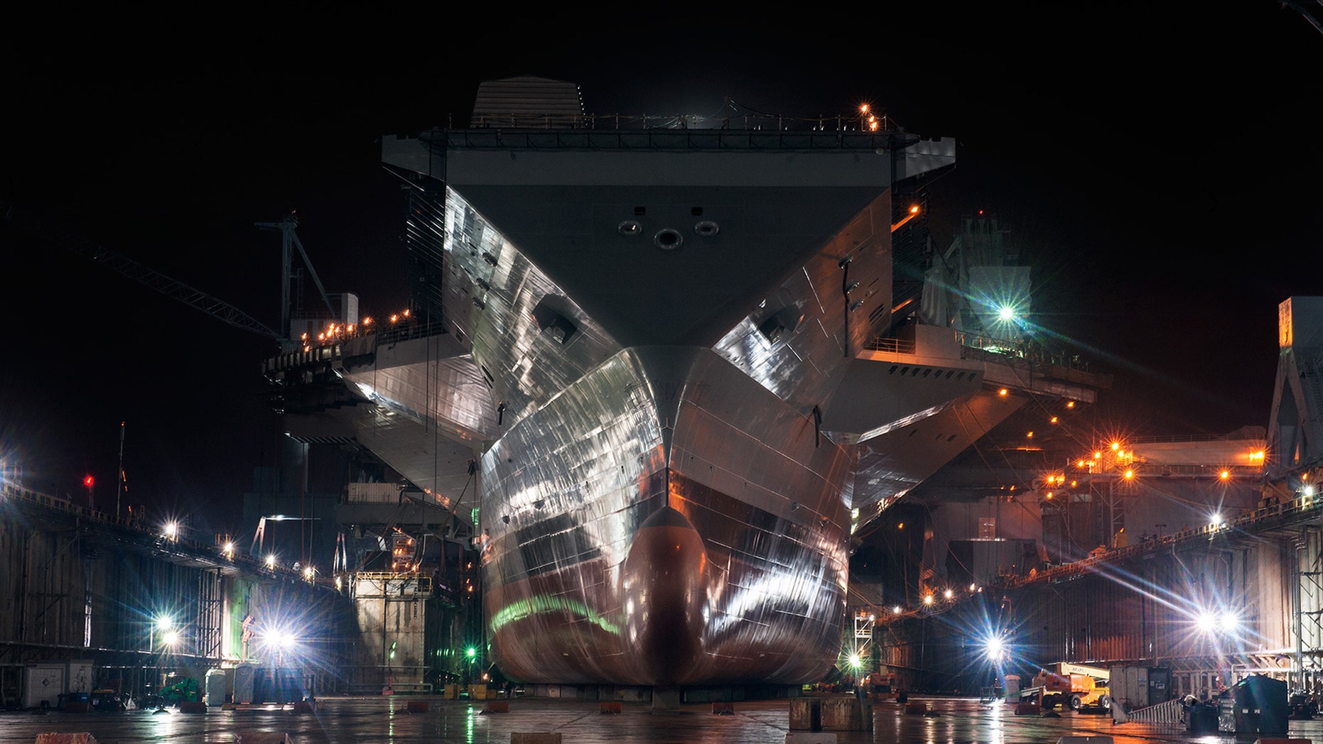 The freshly painted Gerald R. Ford (CVN 78) shines at night in the empty dry dock, waiting to meet water for the first time. Photo by John Whalen.