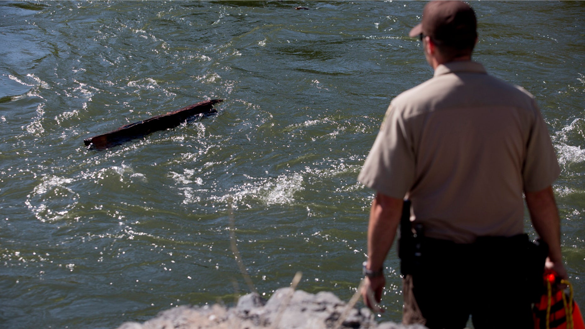 In this Monday, May 29, 2017 photo, police, fire and search and rescue officials respond to a scene along the Provo River near Provo, Utah.