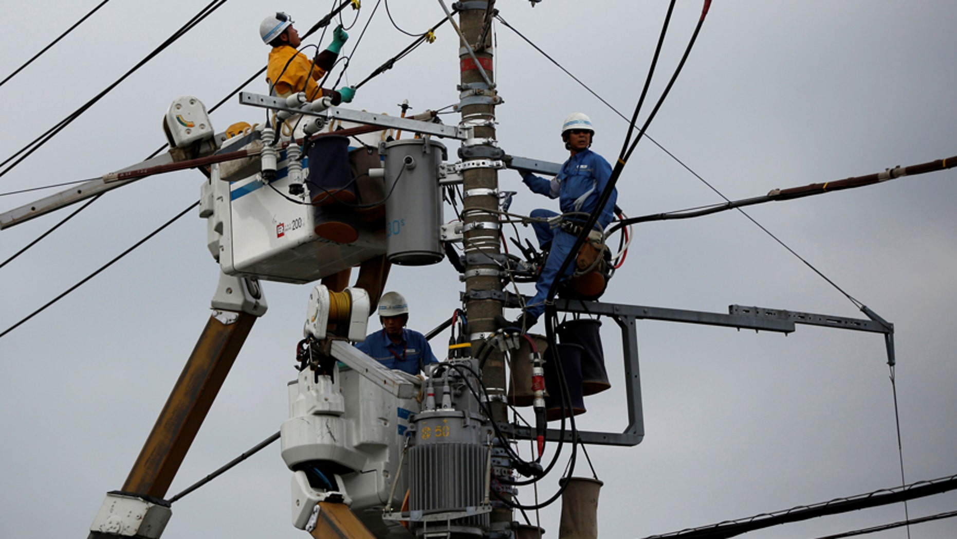 File photo--Men work around an electric utility pole along the street in Urayasu, east of Tokyo October 9, 2014. (REUTERS/Issei Kato/File Photo)