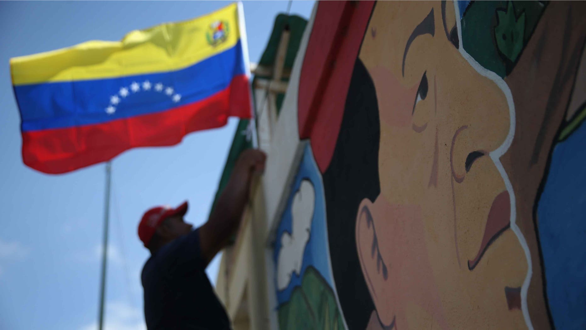 CARACAS, VENEZUELA - MARCH 04: A worker hags a flag outside a military barracks where Hugo Chavez is entombed on March 4, 2014 in Caracas, Venezuela. Workers made last minute preparations for Wednesday's ceremony marking the first anniversary of Chavez' death on March 5, 2013. The anniversary has been marred by three weeks protests against the government of Chavez' chosen successor President Nicolas Maduro. (Photo by John Moore/Getty Images)