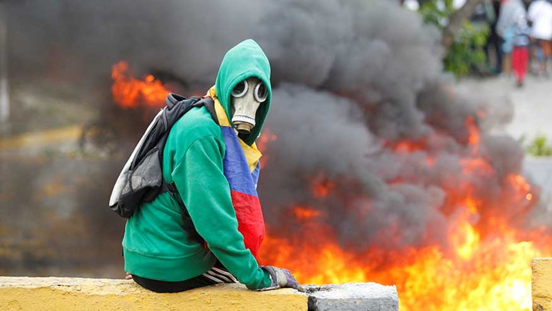 Demonstrator sits next to a fire barricade on a street during a rally against Venezuela's President Nicolas Maduro in Caracas, Venezuela April 24, 2017. REUTERS/Christian Veron - RTS13RH3