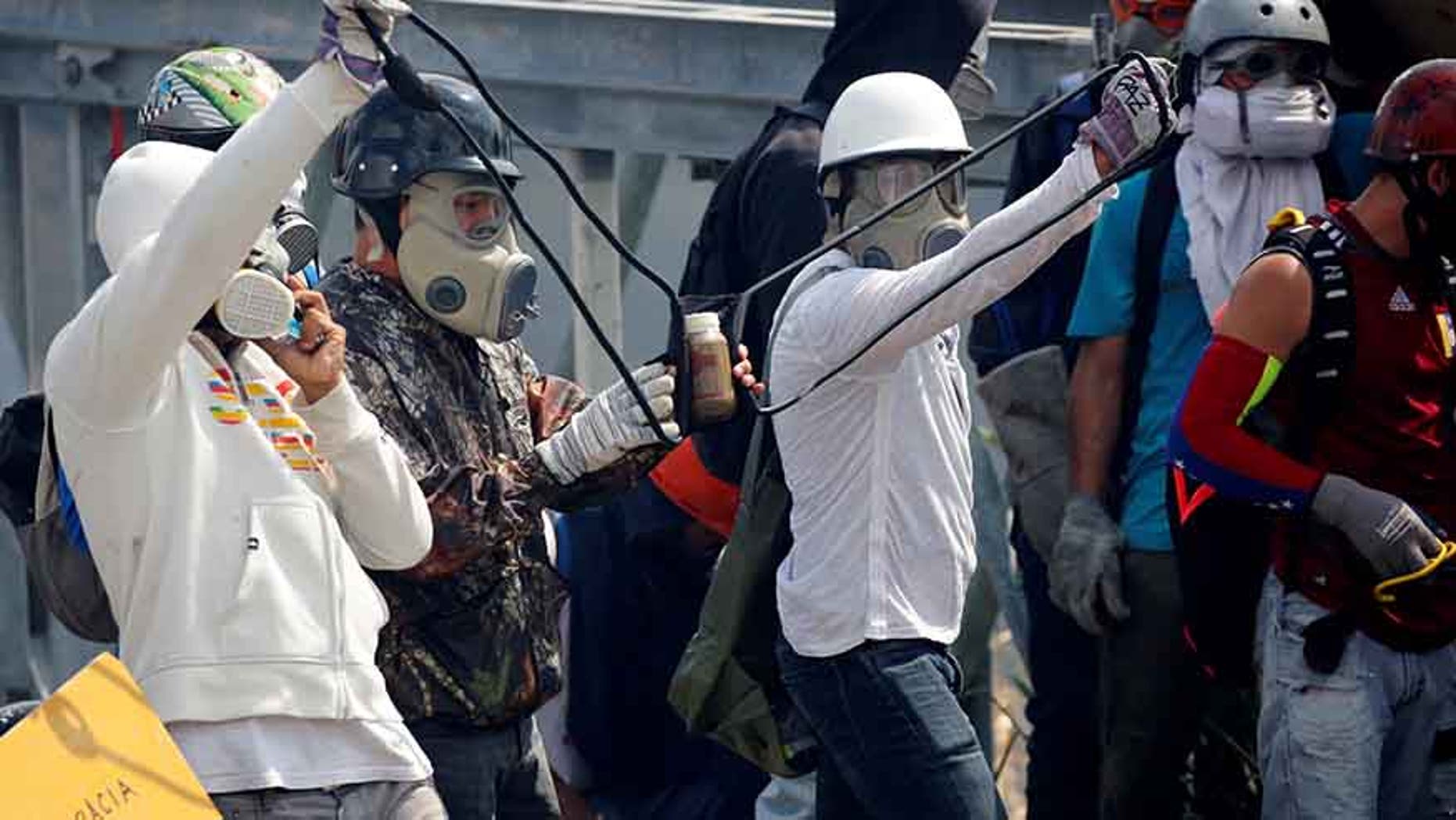 Opposition supporters use a giant sling shot to throw a "Poopootov," a bottle filled with feces, which is a play on Molotov, during a rally in Caracas, Venezuela, May 10, 2017.