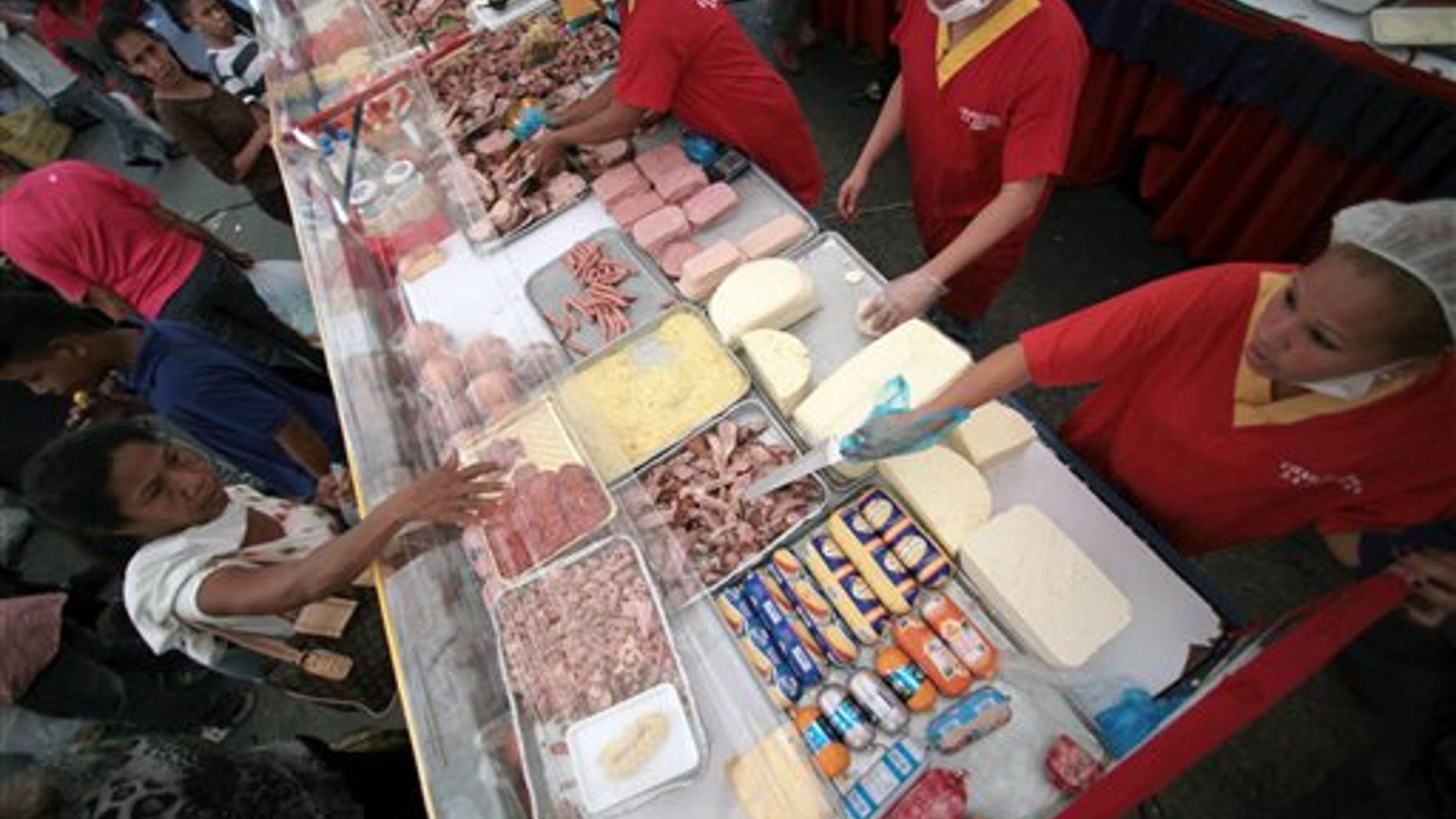 FILE - In this Dec. 15, 2012 file photo, people buy government subsidized food at a state-run market, one day before state elections for governors and legislators, in Caracas, Venezuela. The government is rolling out a new ID system on Tuesday, April 1, 2014 to track families purchases of government subsidized groceries. President Nicolas Maduros administration says the cards to track families purchases will foil people who stock up on groceries at subsidized prices and then illegally resell them for several times the amount. (AP Photo/Fernando Llano, File)