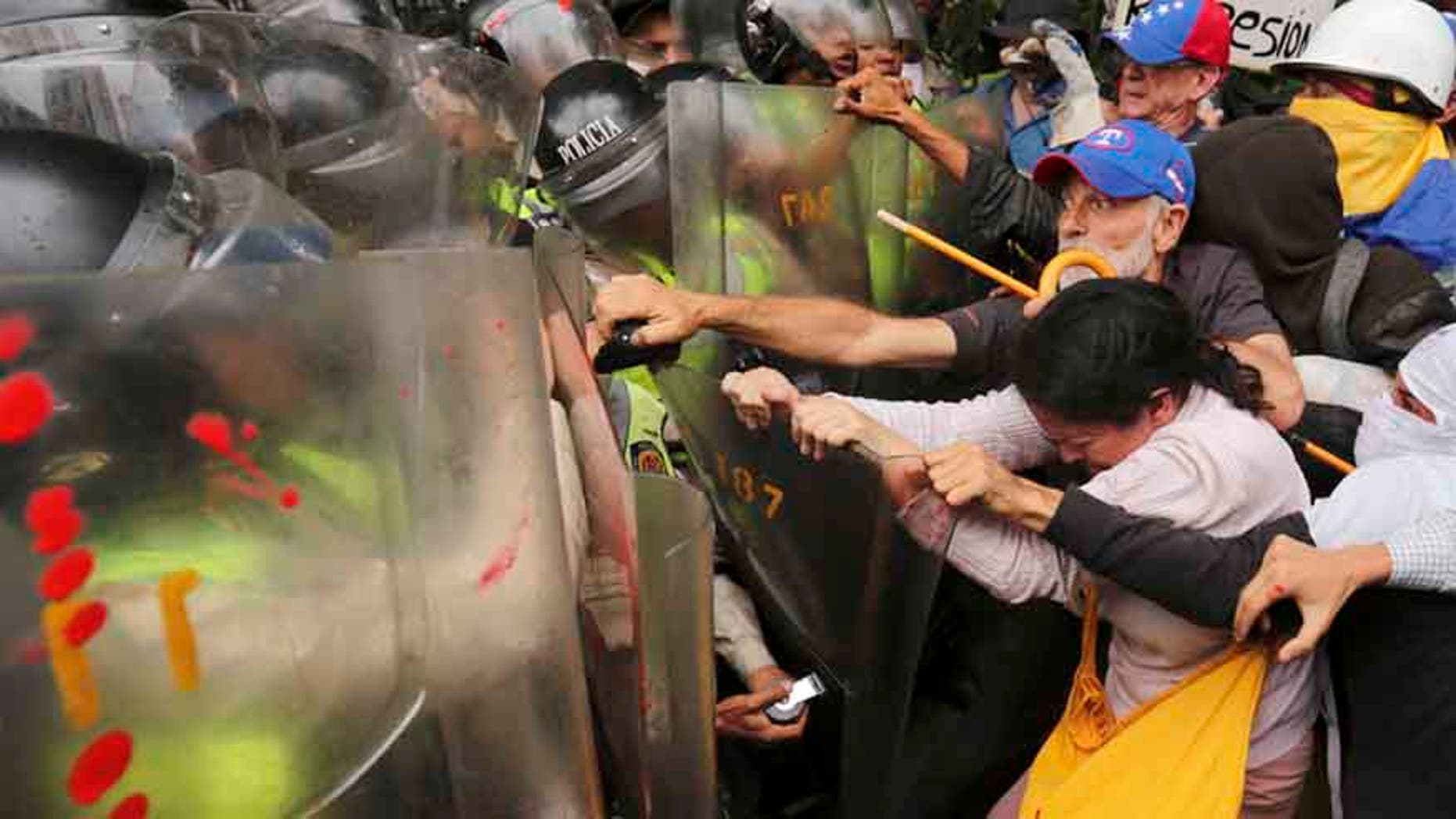 Anti-government protesters scuffle with police blocking older Venezuelans from marching to the Ombudsman's Office in protest of President Nicolas Maduro in Caracas, Venezuela, Friday, May 12, 2017.