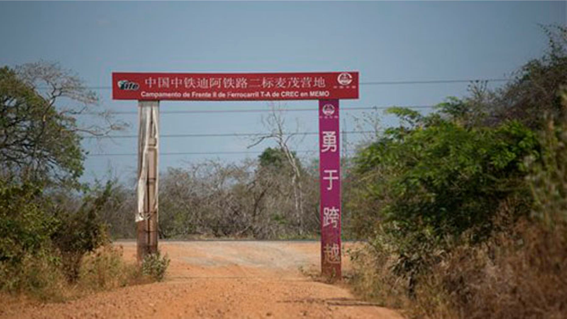 This March 21, 2016 photo shows the entrance to a railroad workers complex that was all but abandoned by its Chinese managers, in Chaguaramas, Guarico state, Venezuela. The red arched sign in Chinese and Spanish is all that remains of what was a bustling complex of 800 workers. (AP Photo/Ariana Cubillos)