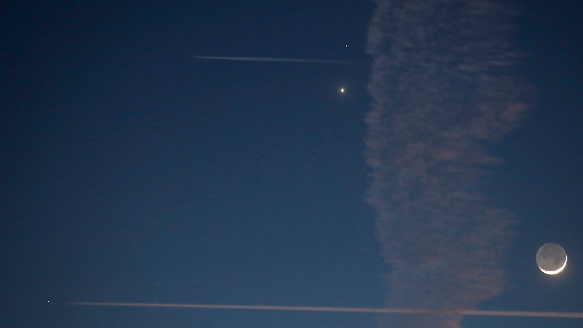 File photo: Aircraft fly past with the crescent moon and planets Venus and Mars visible in the sky in central Bosnia February 20, 2015. People in Bosnia witnessed late Friday evening an astronomical event whereby Venus and Mars were accompanied by a crescent moon just after sunset. (REUTERS/Dado Ruvic)