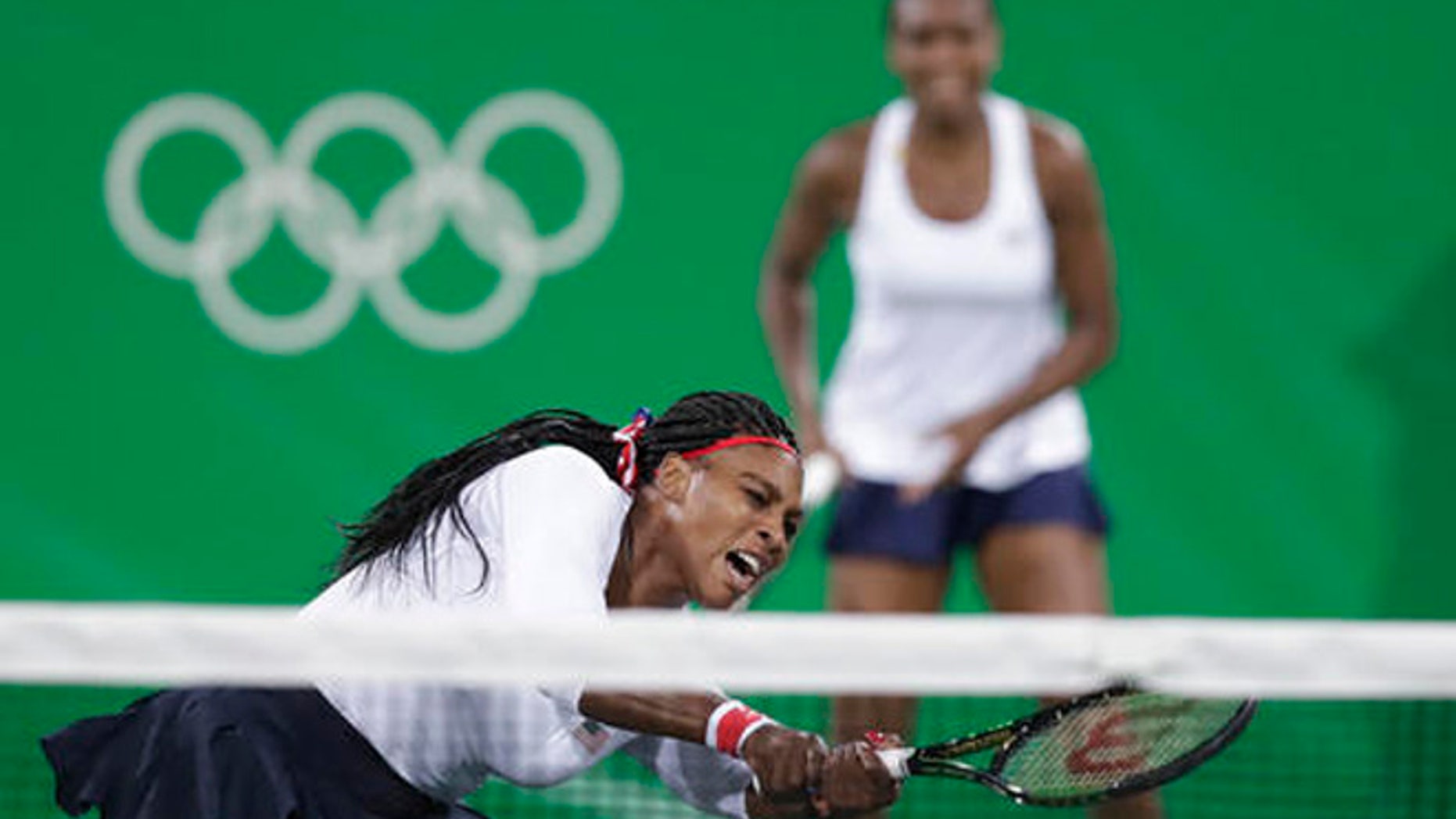 Serena Williams, of the United States, reacts after losing a point at the net in a doubles match with her sister Venus, rear, against Lucie Sarfarova and Barbora Strycova, of the Czech Republic, at the 2016 Summer Olympics in Rio de Janeiro, Brazil, Sunday, Aug. 7, 2016.