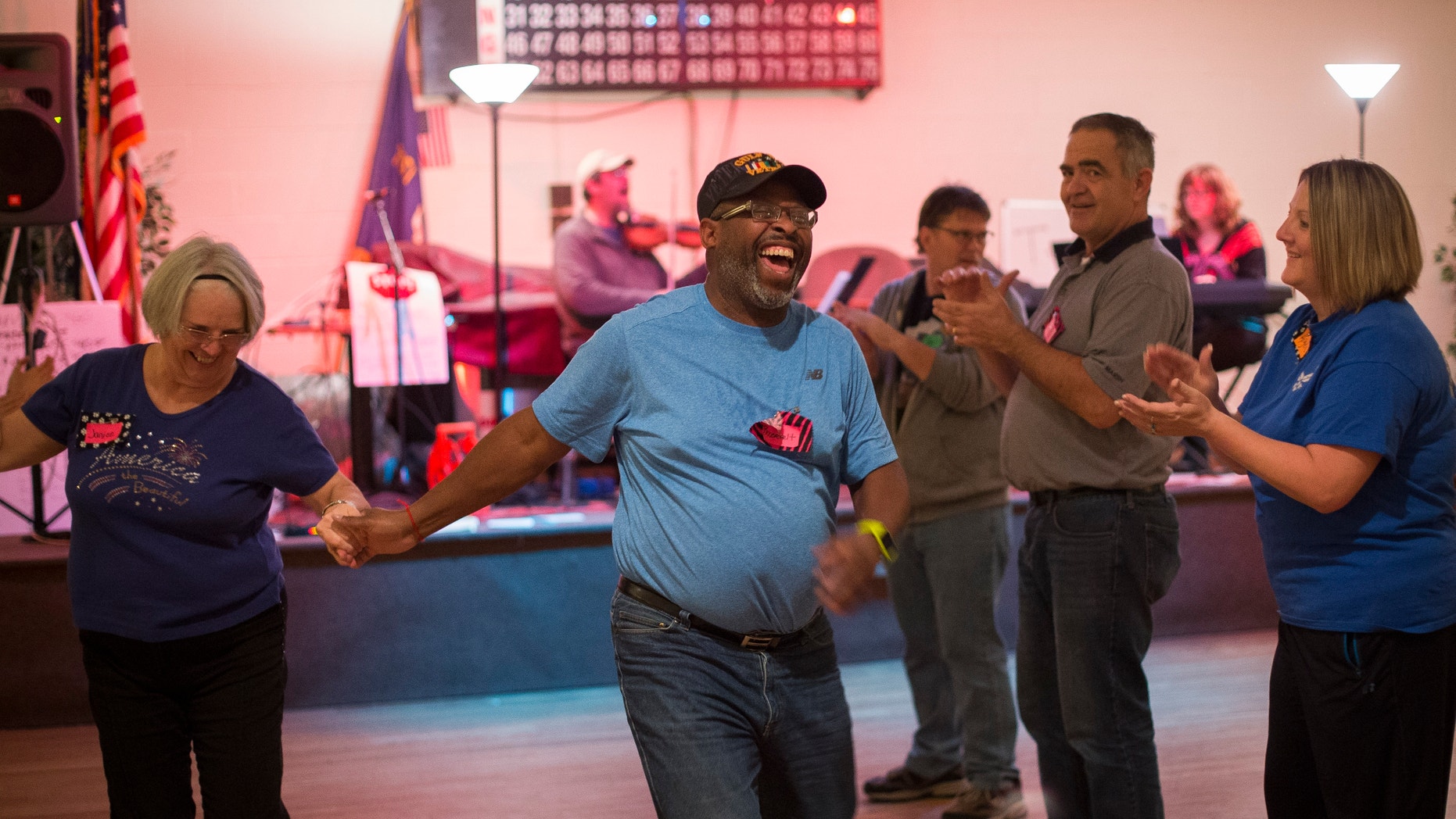 In this Tuesday, Nov. 29, 2016 photo, U.S. Army veteran Roosevelt Smith III, center, enjoys time with other veterans and volunteers in an evening of community dance designed for veterans and families who are affected by PTSD, in Louisville, Ky. The environment is built for maximum comfort: lights are kept low for dancers with traumatic brain injuries, the music is cheery without heavy beats and the location is not advertised to provide anxious visitors a sense of security and privacy. The group sessions are kept small, usually less than 30 people (AP Photo/ David Stephenson)