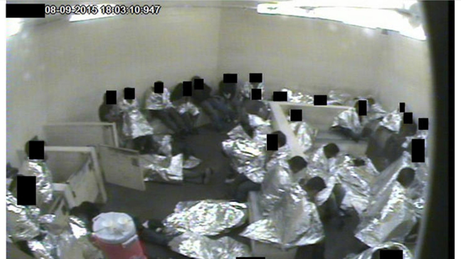 Surveillance camera image of men sitting in a Tucson Border Patrol holding cell wrapped in Mylar sheets. (U.S. Border Patrol)