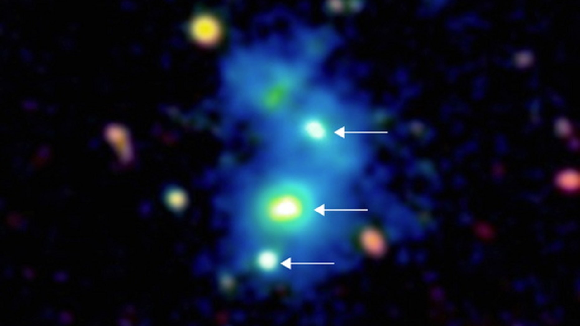 This image shows a rare view of four quasars, indicated by white arrows, found together by astronomers using the Keck Observatory in Hawaii. The bright galactic nuclei are embedded in a giant nebula of cool, dense gas visible in the image as a