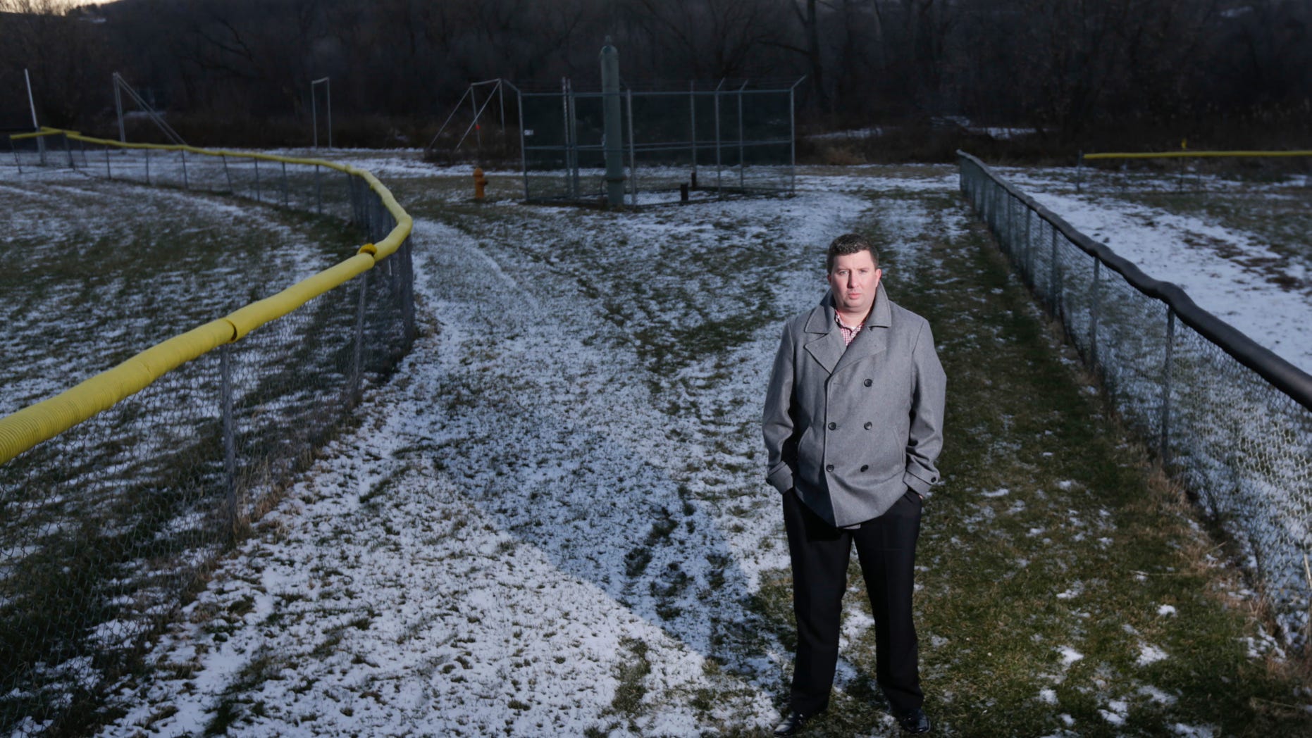 In this Thursday, Jan. 21, 2016 photo, Michael Hickey poses near Hoosick Falls municipal well 7 between two baseball fields in Hoosick Falls, N.Y. Federal regulators have warned residents of an upstate New York factory village near the Vermont border not to drink water from municipal wells, and a plastics plant has agreed to supply bottled water and pay for a new filtration system. The action this month resulted from a quest by Hickey to find out why so many people in Hoosick Falls had cancer. (AP Photo/Mike Groll)