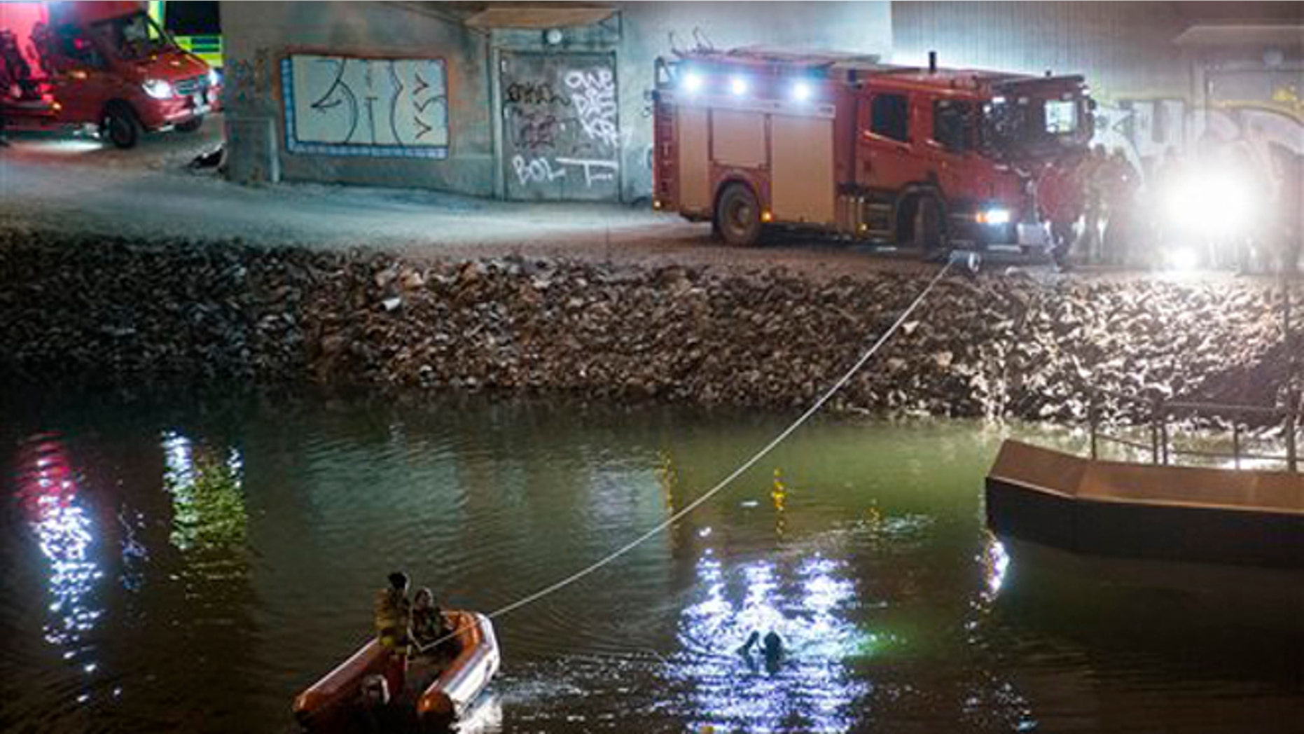 Divers and rescue service personnel search for the victims of the deadly car crash in the canal under the E4 highway bridge in Sodertalje, Sweden, late Saturday, Feb.13, 2016. (Johan Nilsson/TT News Agency via AP)