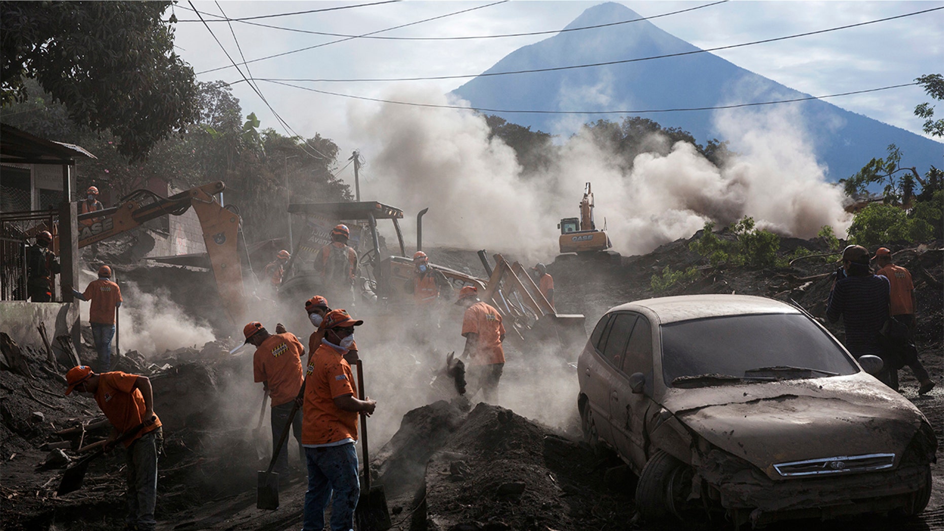 Rescue workers remove piles of ash spewed by the Volcan de Fuego, or "Volcano of Fire," eruption, in El Rodeo, Guatemala, Wednesday, June 6, 2018. Wednesday morning rescuers were concerned about possible dangers posed not only by more volcanic flows but also rain. Authorities have said the window is closing on the chances of finding anyone else alive in the devastation. (AP Photo/Rodrigo Abd)