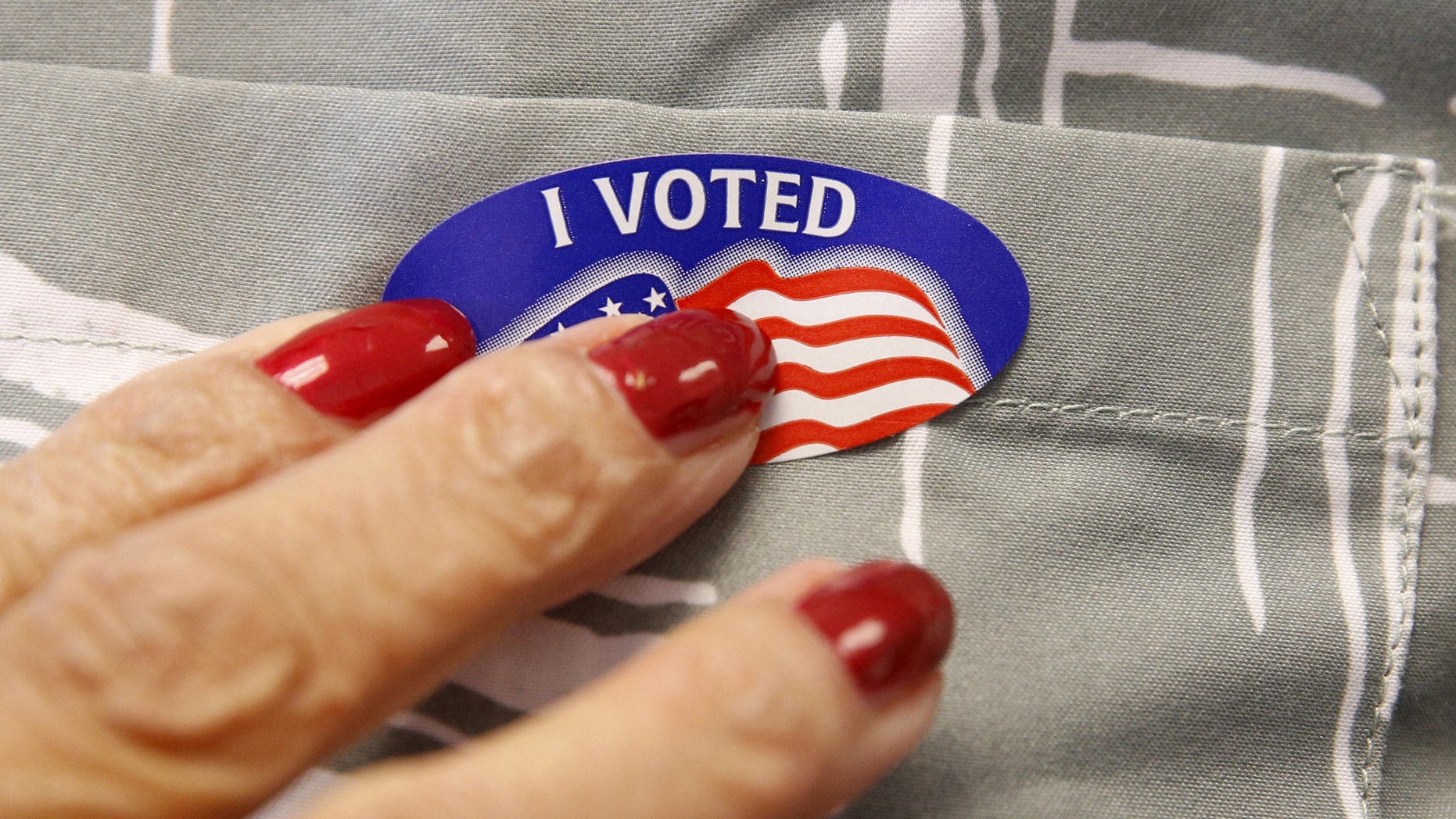 A voter receives a sticker from a polling station worker after he cast his ballot in the Super Tuesday election at Sleepy Hollow Elementary School in Falls Church, Virginia March 1, 2016. (REUTERS/Kevin Lamarque)