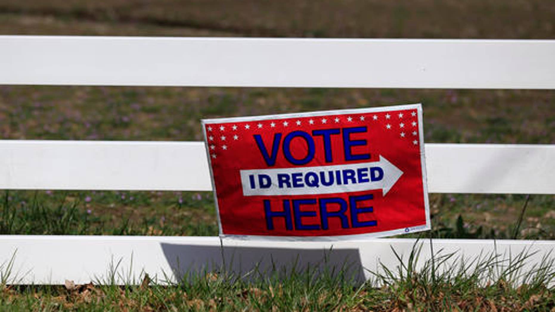 A sign directing voters is posted along a fence line at the Platte County Fair Grounds in Tracy, Mo., Tuesday, March 15, 2016. Voters in Missouri, as well as North Carolina, Illinois, Ohio and Florida are casting their ballots in primary elections Tuesday. (AP Photo/Orlin Wagner)