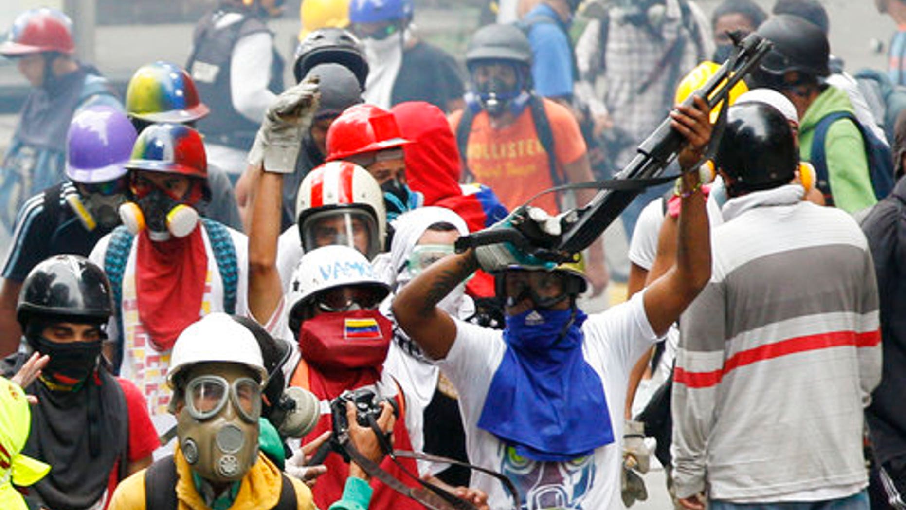 An anti-government demonstrator shows a shotgun taken from security forces during clashes in Caracas, Venezuela, Monday, May 8, 2017,