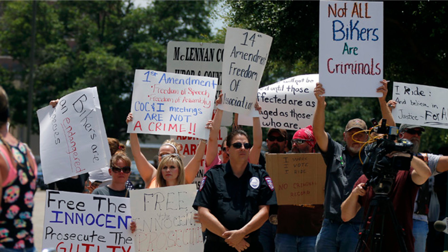 Protestors stand on a corner as bikers arrive for the "All for 1" rally at the McLennan County courthouse in Waco, Texas, Sunday, June 7, 2015. Organizers, who have called the event a peaceful, silent protest, gathered in front of the courthouse to protest what they say is the violation of rights of many bikers who were arrested at Twin Peaks just for being at the scene of the crime. (Rod Aydelotte/Waco Tribune Herald via AP)