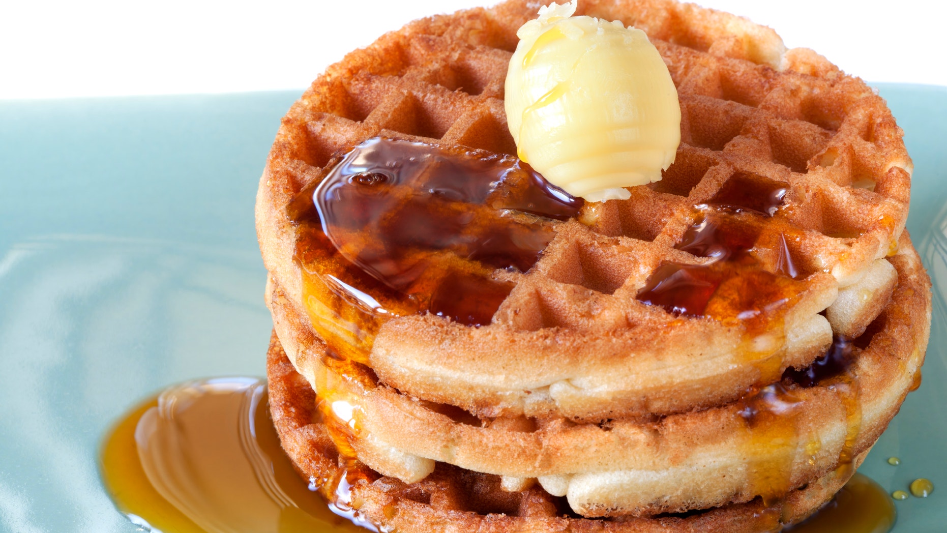 Stack of waffles with maple syrup and butter.