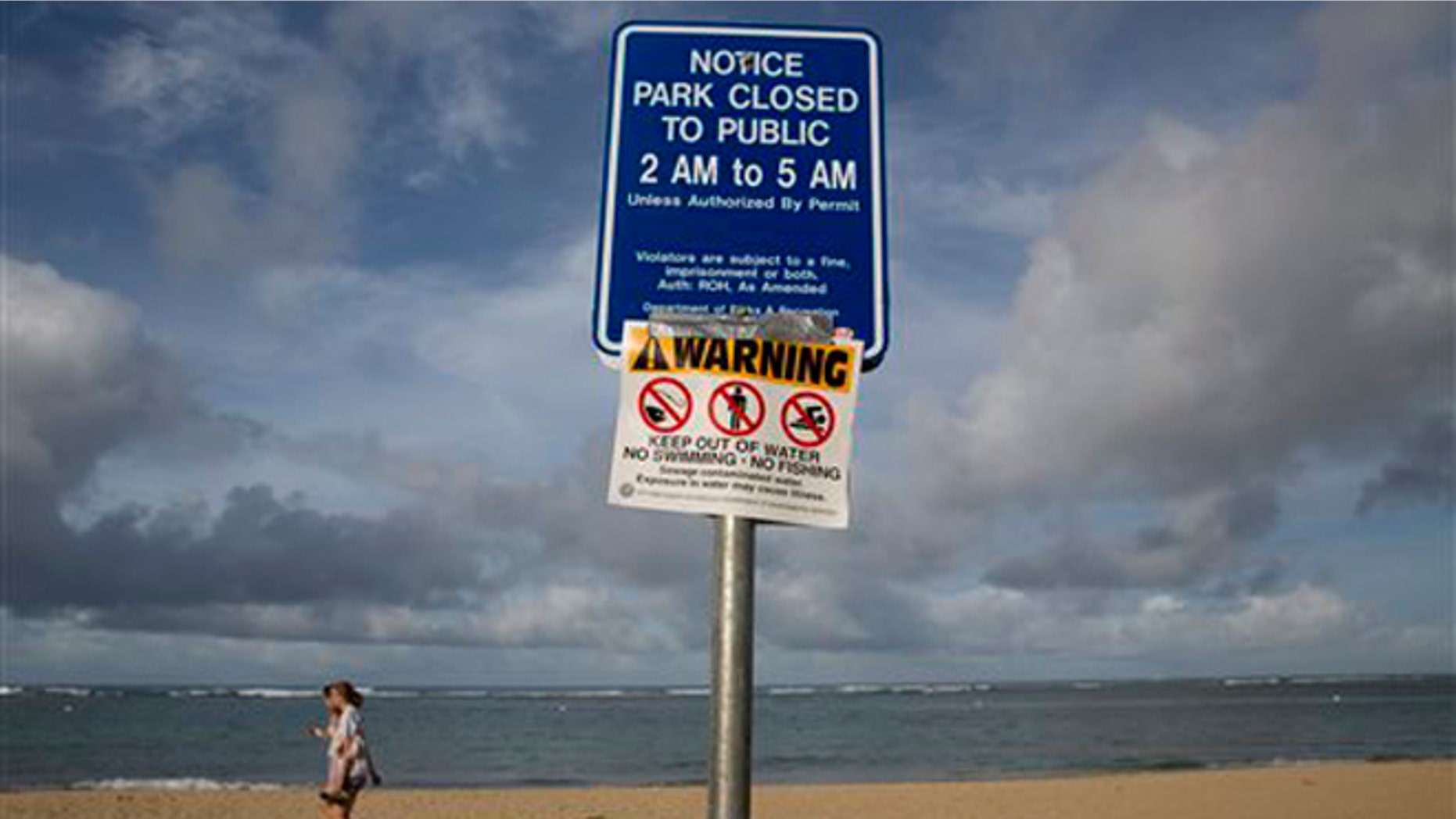 Aug. 25, 2015: Tourists walks near a warning sign posted on Waikiki Beach in Honolulu. Most of the famed beach fronting Waikiki was closed after heavy rains triggered a half-million gallon sewage spill near Hawaii's world-famous tourist district, officials said.
