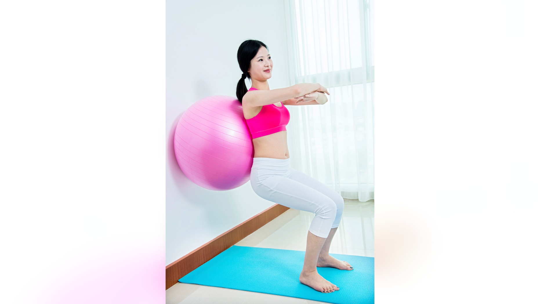Young asian woman working out with fitness ball.