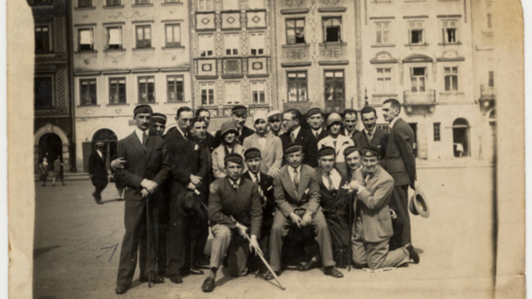 A group of friends, many of whom are wearing university caps, pose for a group portrait on a street in Warsaw. The photo is on display at the United States Holocaust Memorial Museum