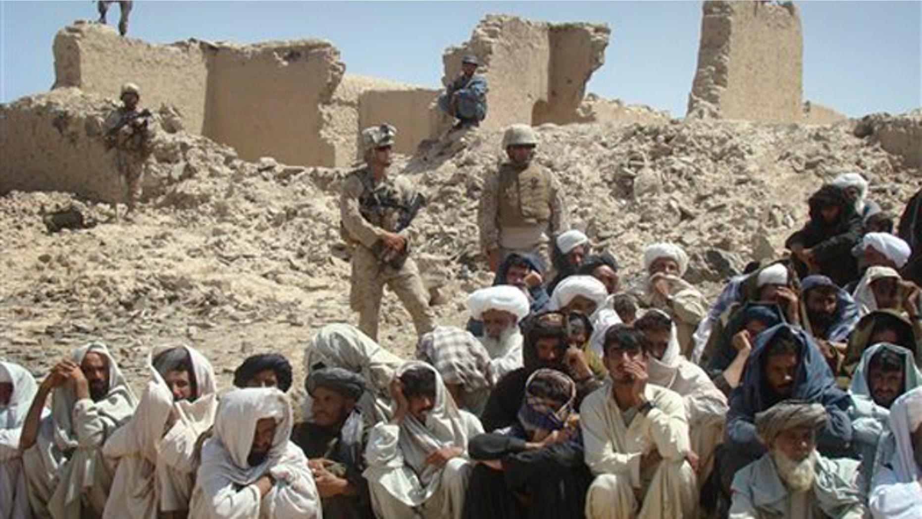 In this Aug. 27 photo, Afghan men listen to speeches, as Afghan and U.S. soldiers stand guard, background, in Washer district south of Kabul, Afghanistan.