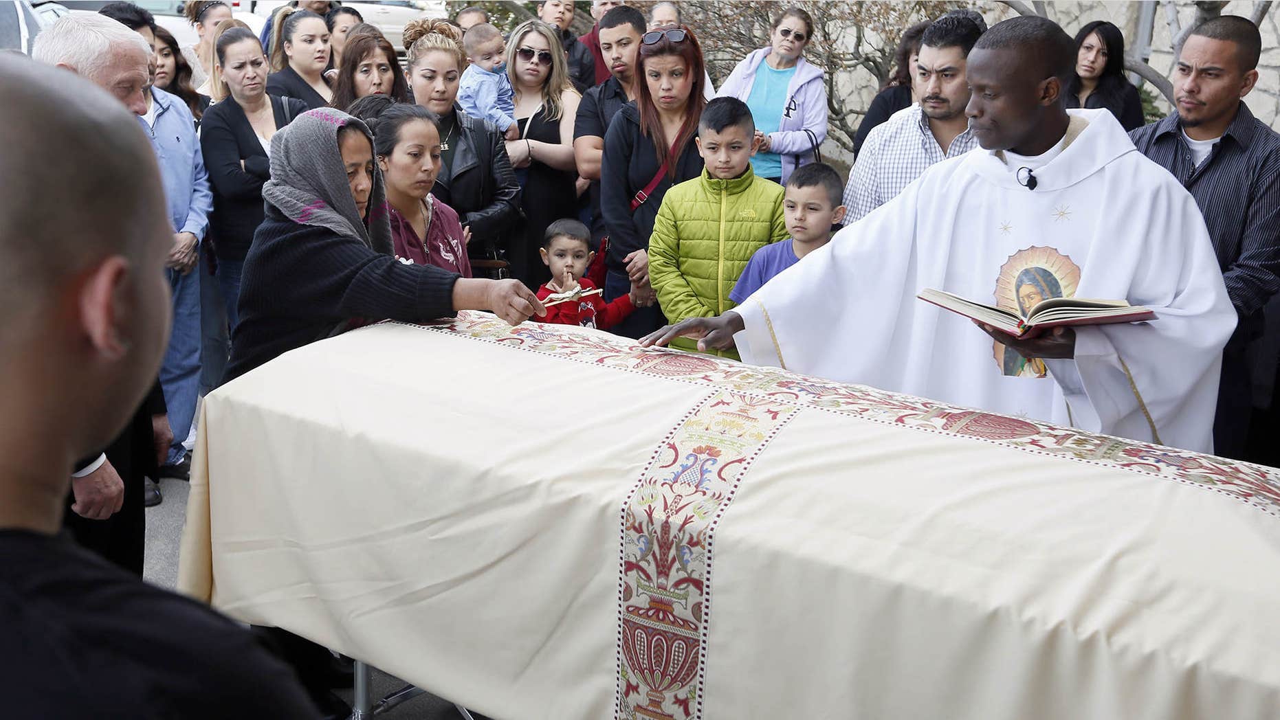Feb. 25, 2015: Agapita Montes-Rivera, left, places a crucifix on the coffin of her son, Antonio Zambrano-Montes during his funeral service conducted by Rev. Lutakome Nsubuga.