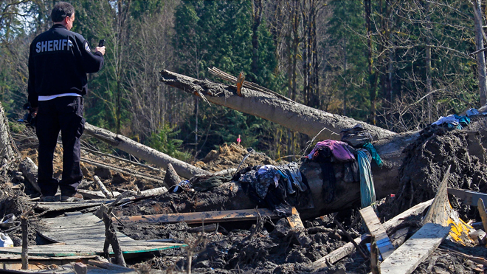 April 1, 2014: A sheriff official takes photos of debris from a massive fatal mudslide near Oso, Wash. The March 22 mudslide destroyed a rural mountainside community northeast of Seattle.