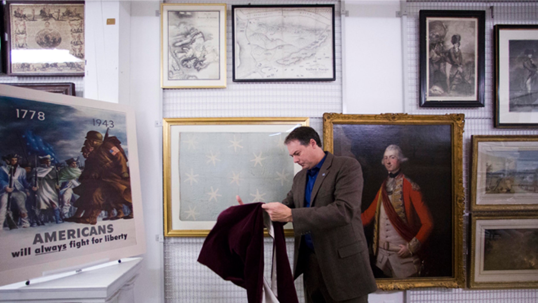 June 5, 2014: In this photo during an interview with the Associated Press Scott Stephenson, Director of Collections and Interpretation, uncovers the recently conserved George Washington's flag, which flew to denote his presence at various battles during the war against Britain, at the Museum of the American Revolution's facility near Philadelphia.
