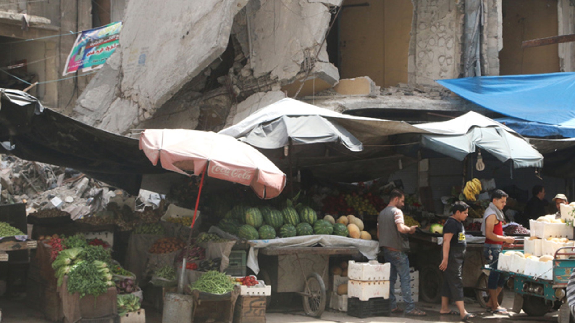 Vendors wait for customers near their stalls erected in front of damaged buildings during the holy month of Ramadan in the rebel held area of Aleppo's al-Shaar district, Syria, June 15, 2016. REUTERS/Abdalrhman Ismail - RTX2GDRZ