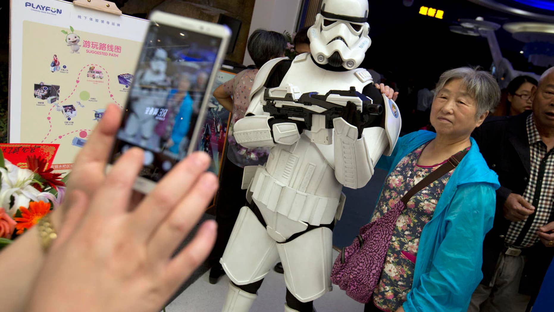 A Chinese woman poses for a photo with a worker dressed in a storm trooper costume at the Wanda Mall outside of the Wanda Cultural Tourism City in Nanchang in southeastern China's Jiangxi province, Saturday, May 28, 2016. The Walt Disney Co. owns the rights to Lucas Film and associated properties.