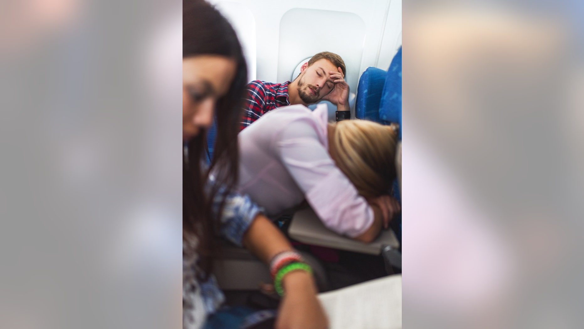 People traveling by airplane. Focus is on background, on young man sleeping.