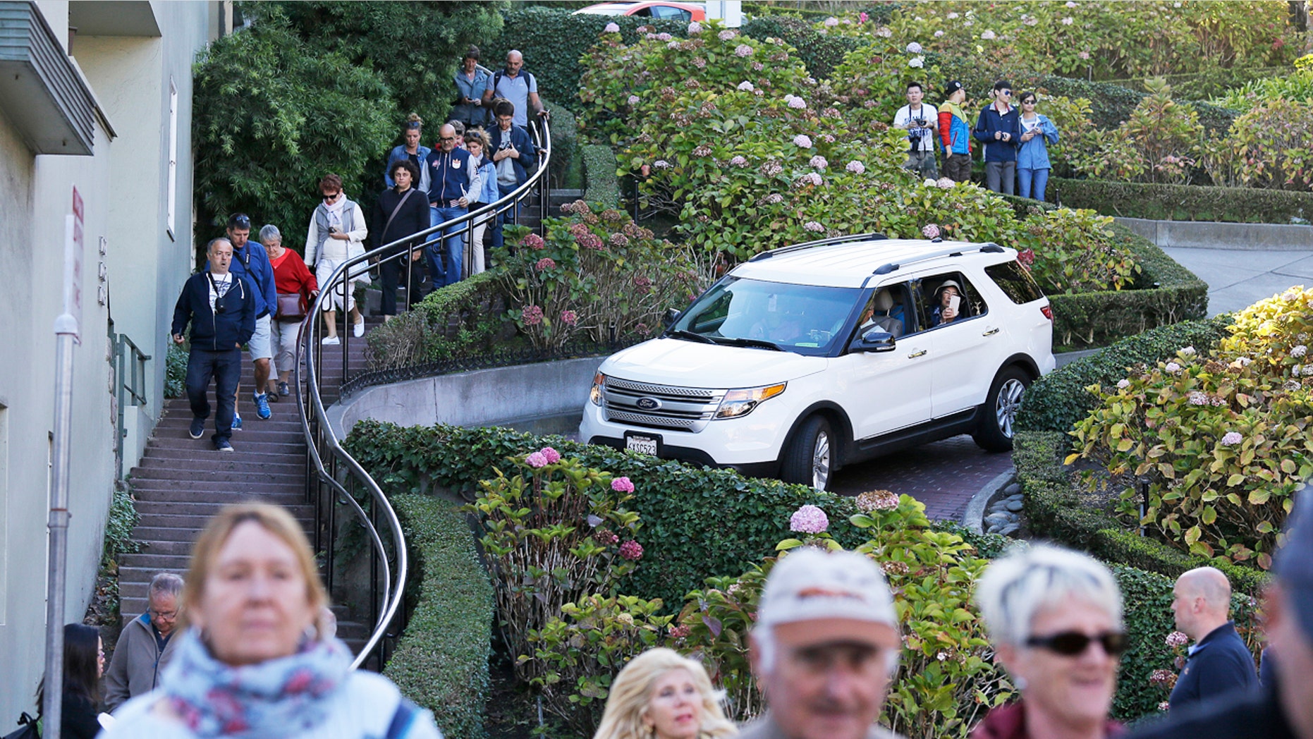 Tourists make their way down Lombard Street, also known as the "most crooked street" in San Francisco. The crooked block has become so chaotic that the city of San Francisco is considering solutions as drastic as banning cars or requiring timed reservations.